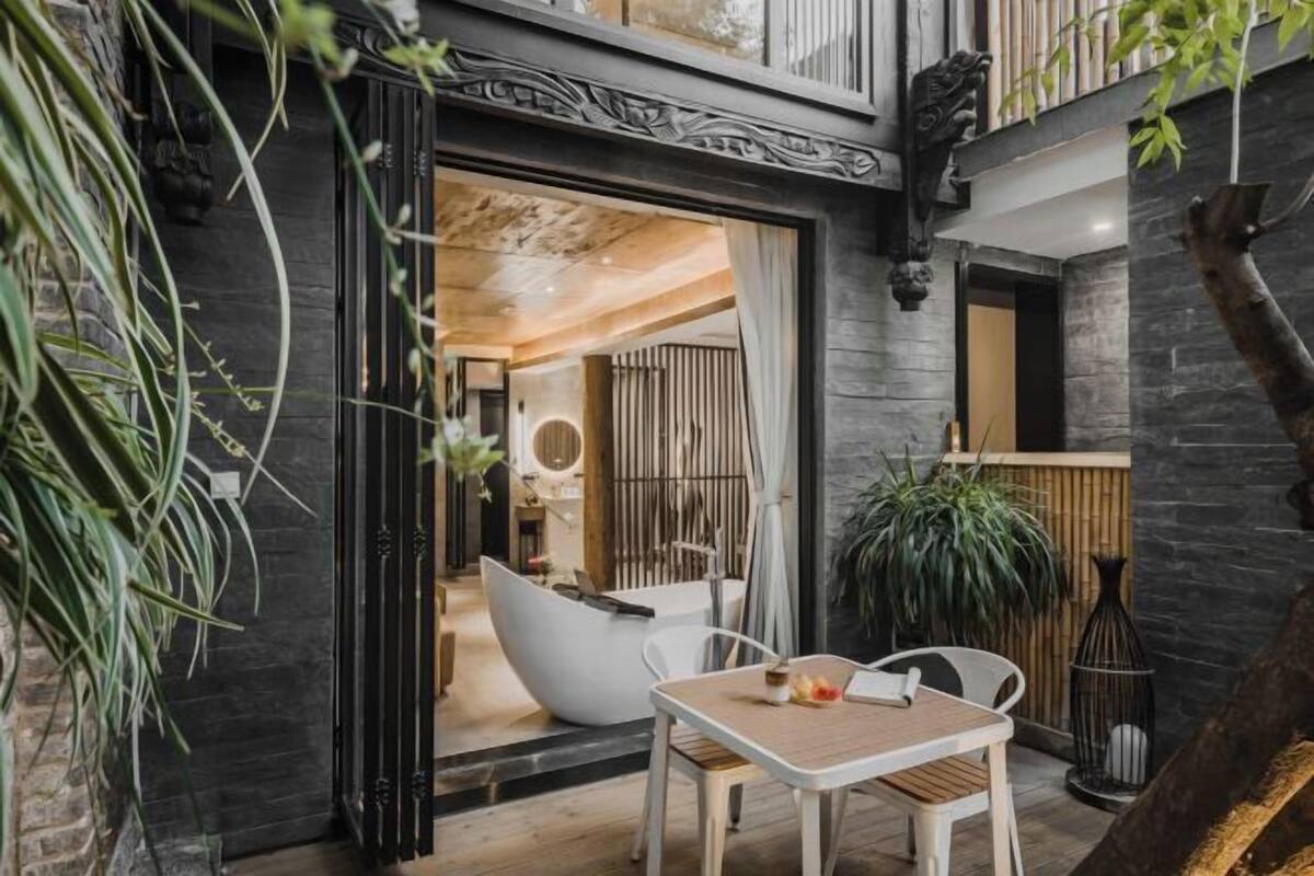 Un espacio interior con diseño moderno, que incluye un comedor con mesa y sillas, una silla blanca con forma de huevo y una planta en maceta.
