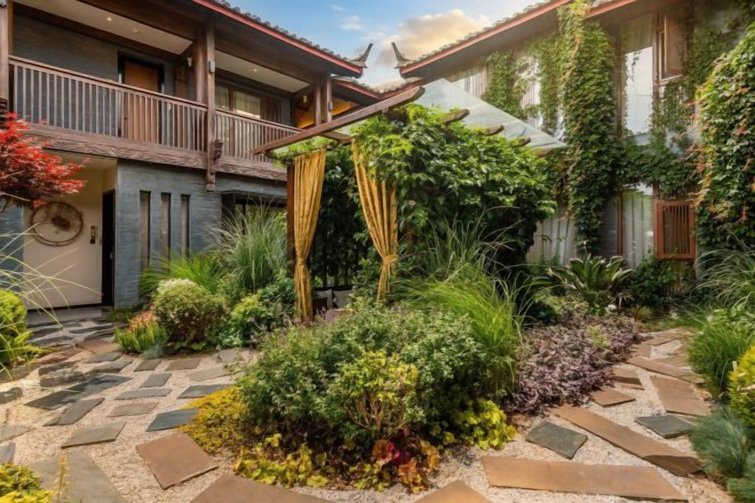 A courtyard with a stone pathway, lush greenery, and a wooden balcony.