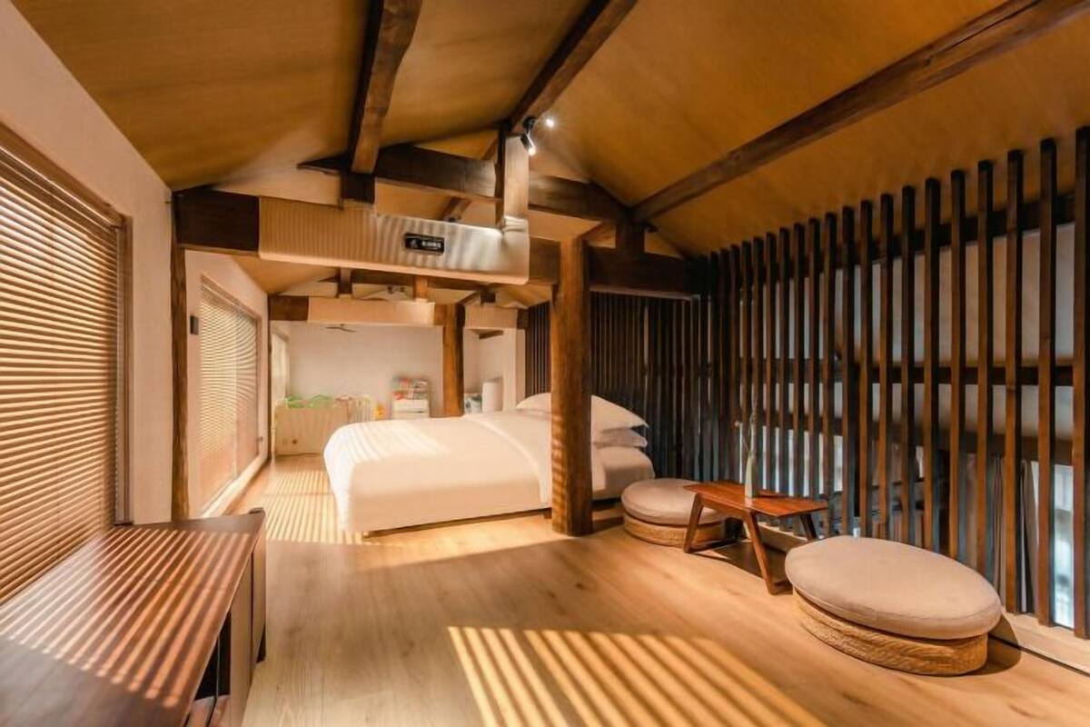 Un dormitorio con cama, mesita de noche y ventana con persianas.