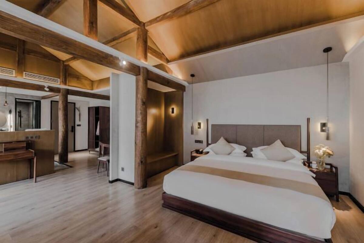 Un dormitorio amplio con una cama grande, vigas de madera y un baño moderno.