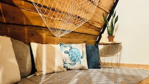 Une pièce chaleureuse avec un hamac, un tapis à motifs et une plante en pot.