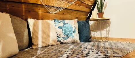 A cozy room with a hammock, patterned rug, and a potted plant.