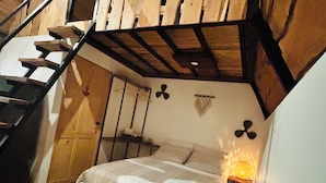 Une chambre avec un lit superposé en bois, une petite table de chevet et un luminaire fixé au mur.