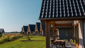 A row of modern, single-story buildings with dark tiled roofs and wooden structures. - Dune Lodge on a Holiday Park, Beach at 1.3 km (Cadzand-Bad)