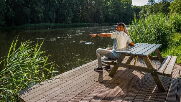 A wooden dock extending over a calm river, surrounded by lush greenery. - Colorful Chalet Near Amsterdam (Amstelveen)