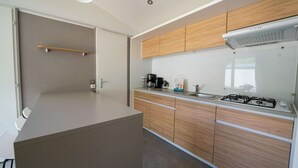 A modern kitchen with wooden cabinets, a stainless steel sink, and a gas stove. - Colorful Chalet Near Amsterdam (Amstelveen)
