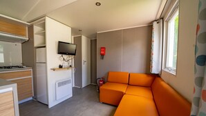 A compact kitchen with a stove, refrigerator, and a flat-screen TV mounted on the wall. - Colorful Chalet Near Amsterdam (Amstelveen)