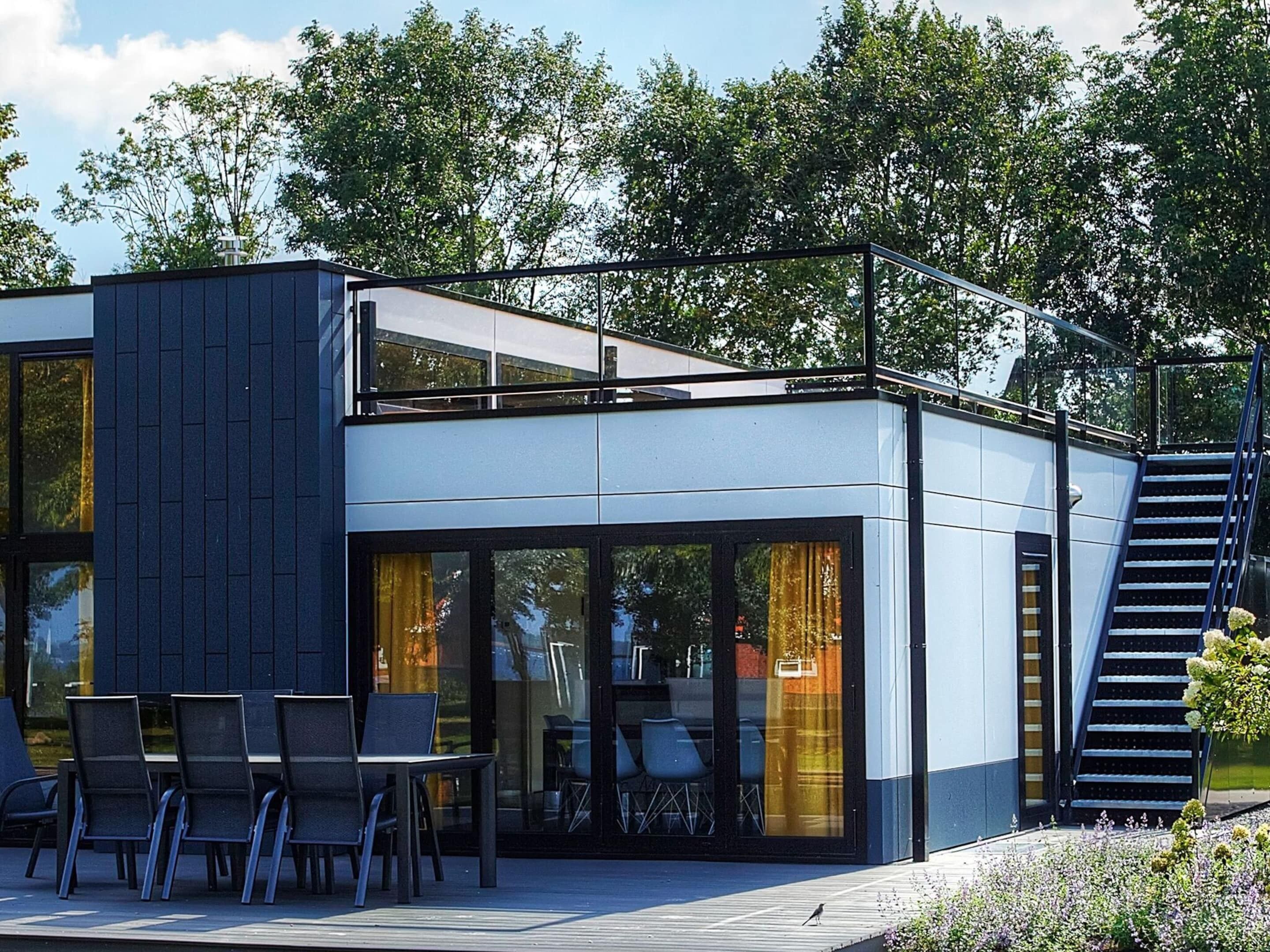 Un bâtiment moderne à deux étages, doté d’une façade en verre, d’un espace extérieur aménagé pour s’asseoir et d’un escalier menant à l’étage supérieur.