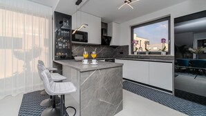 A modern kitchen with a marble countertop, a bar area, and a view of the city through a large window. - Gorgeous home in Privlaka (Privlaka)