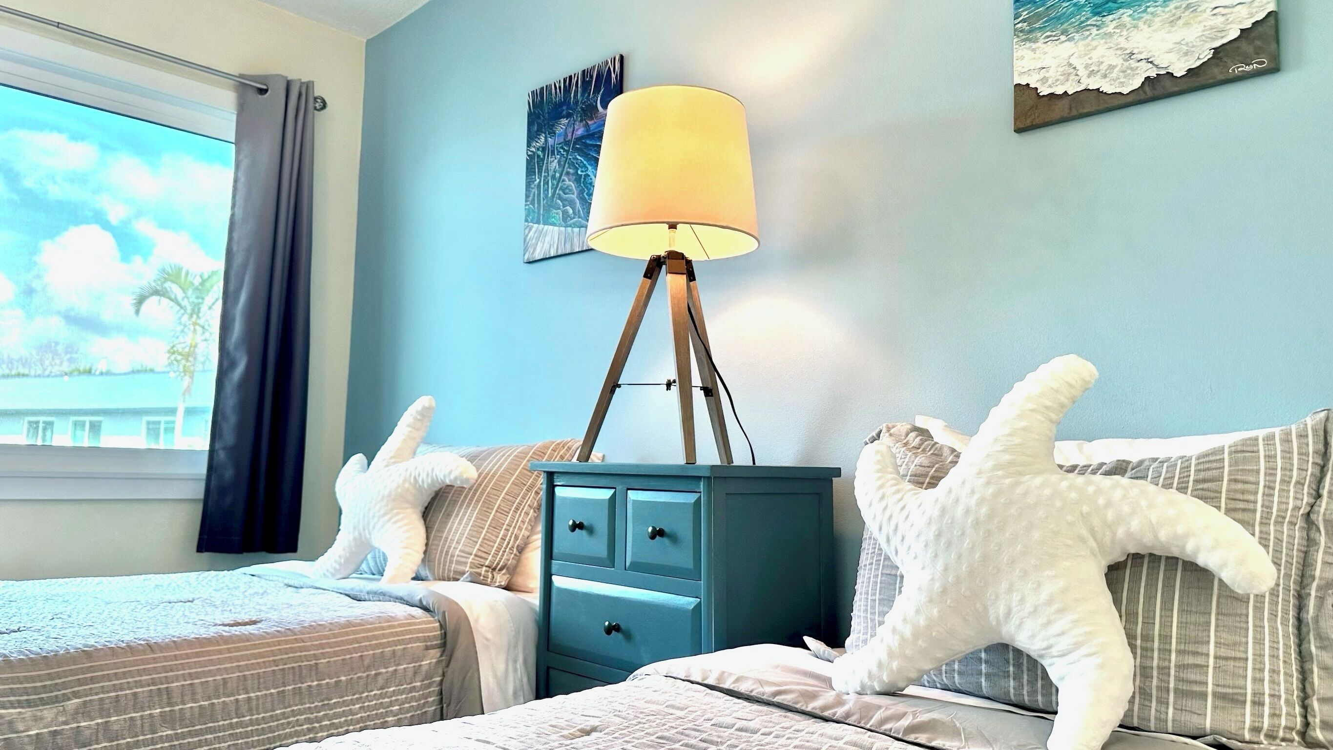 A bedroom with two beds, a nightstand, a lamp, and a painting on the wall.