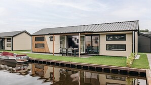 A modern house with a pool, a boat, and a patio area. - Fenced Garden Family Chalet (Giethoorn)