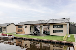 Ett modernt hus med pool, en båt och en uteplats.