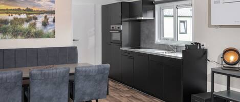A modern kitchen with dark cabinetry, a built-in oven, and a window above the sink.