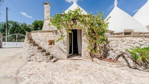 A stone building with a doorway, a stone staircase, and a white conical roof. - White Conus by Rentbeat (Ostuni)