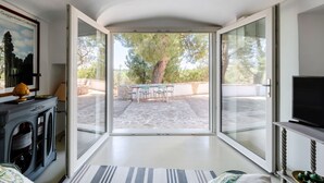 A room with a large sliding glass door leading to an outdoor patio with a table and chairs. - White Conus by Rentbeat (Ostuni)
