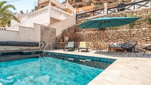 Une piscine avec un mur en pierre et un escalier menant à un balcon.