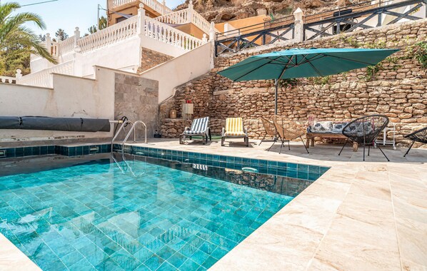 Piscina com parede de pedra e escadaria para um balcão.