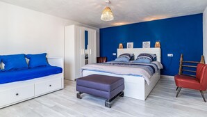 Une chambre à coucher comprenant un lit, un canapé, une chaise et un luminaire suspendu.