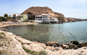 Um hotel à beira-mar com escarpa rochosa, praia e águas cristalinas.