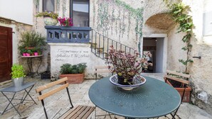 A courtyard with a round table, wooden benches, potted plants, and a staircase. - Beautiful apartment in Filignano with WiFi (Filignano)
