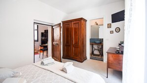 A bedroom with a large bed, a wardrobe, a desk with a chair, and a bathroom visible through an open door. - Beautiful apartment in Filignano with WiFi (Filignano)