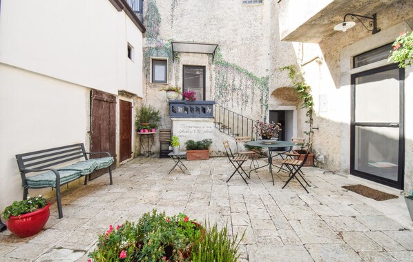 Un cortile con una panchina, un tavolo e sedie, e piante in vaso.