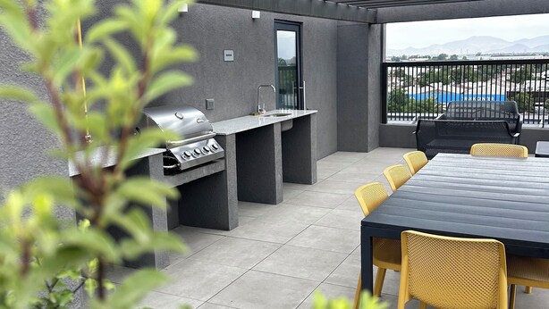 Eine Außenpatio mit Grill, Sitzgelegenheit und Blick auf die Stadtlandschaft.