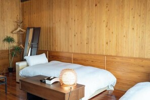 Quarto com painéis de madeira, uma cama, mesa de cabeceira e um cabideiro.