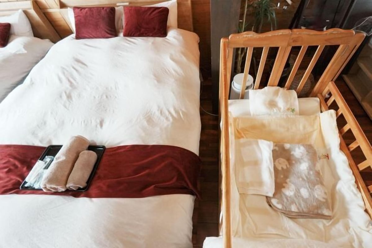 A hotel room with a large bed, a wooden chair, and a small table with a tray.