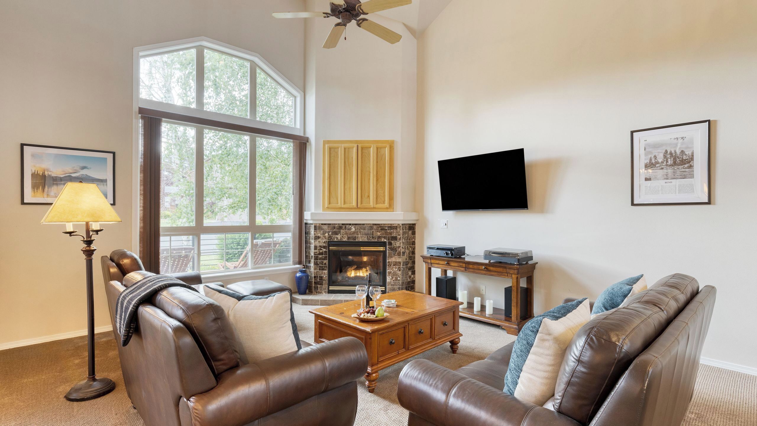 A living room with leather sofas, a fireplace, a television, and a large window.