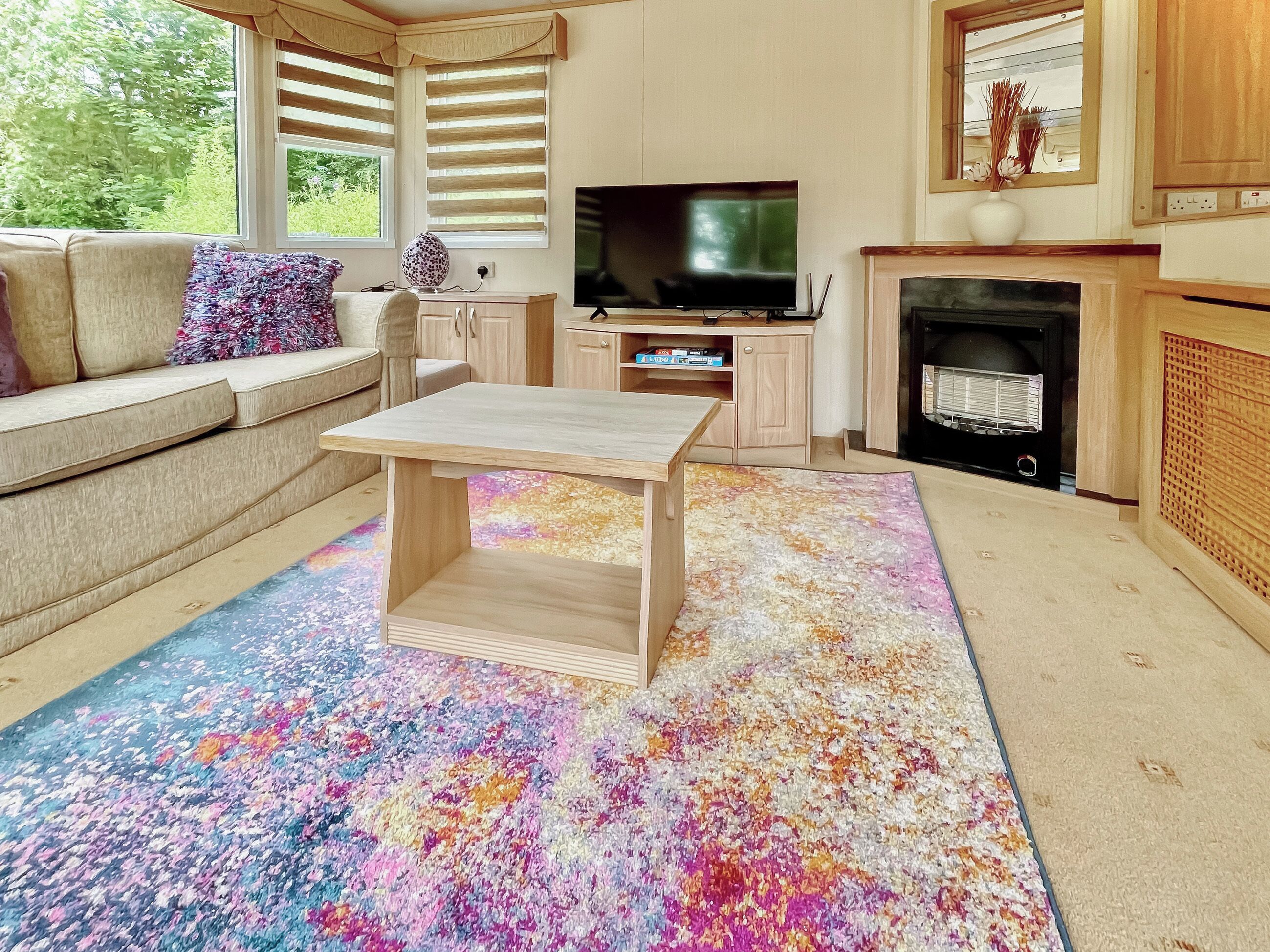 Ein Wohnzimmer mit Sofa, Couchtisch, Fernseher und Kamin.