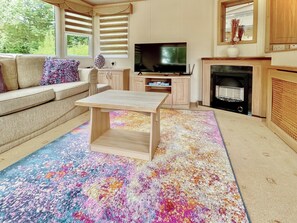 A living room with a sofa, a coffee table, a TV, and a fireplace. - Shirley's Haven - UK46631 (Driffield)