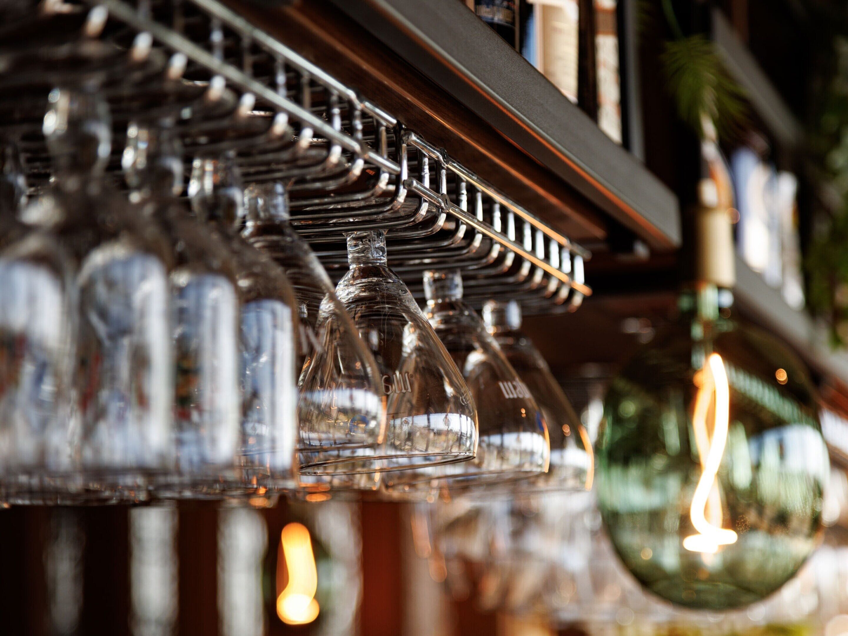 Un espace bar doté d’une étagère métallique où sont rangées de nombreuses bouteilles et verres en verre.