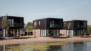 A modern, multi-story building with large windows and outdoor seating areas. - Luxurious Lodge in a Holiday Park (Zwartewaal)