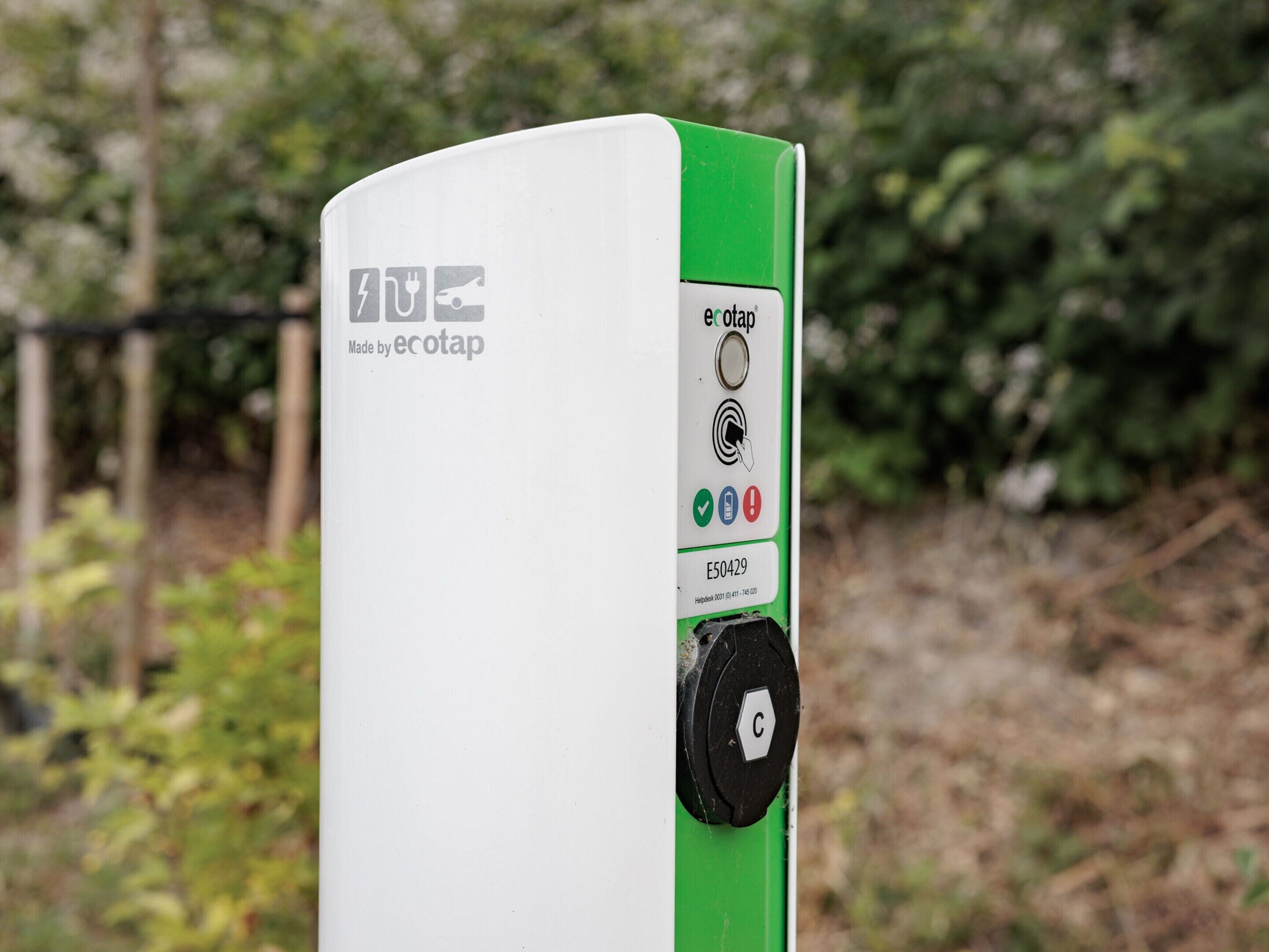 A charging station with a white and green color scheme, a logo, and a circular button.
