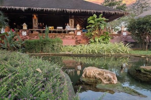 A traditional thatched-roof structure with a pool and lush greenery. - Parntel Khao Yai (Pak Chong)