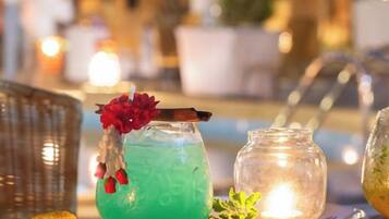 Cocktail-drinkki, jossa on kukka koristeena, tarjoiltuna pöydällä, jonka päällä on kynttilä ja lasipurkki.