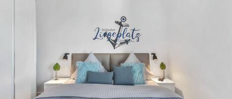 A bedroom with a bed, two bedside tables with lamps, and a wall decoration.