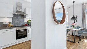 Moderni keittiö, jossa on valkoiset kaapit, Bosch-uuni ja suuri ikkuna, josta avautuu näkymä kaupunkimaisemaan.