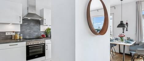 A modern kitchen with white cabinets, a Bosch oven, and a large window overlooking a cityscape.