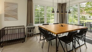 Un comedor moderno con una gran mesa de madera, sillas negras y luces colgantes.