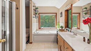 A bathroom with a bathtub, a sink, a window with a view of trees, and a mirror. - Poconos Escape w/ Game Room, Poker Loft, Fire Pit + Spacious Deck (Albrightsville)