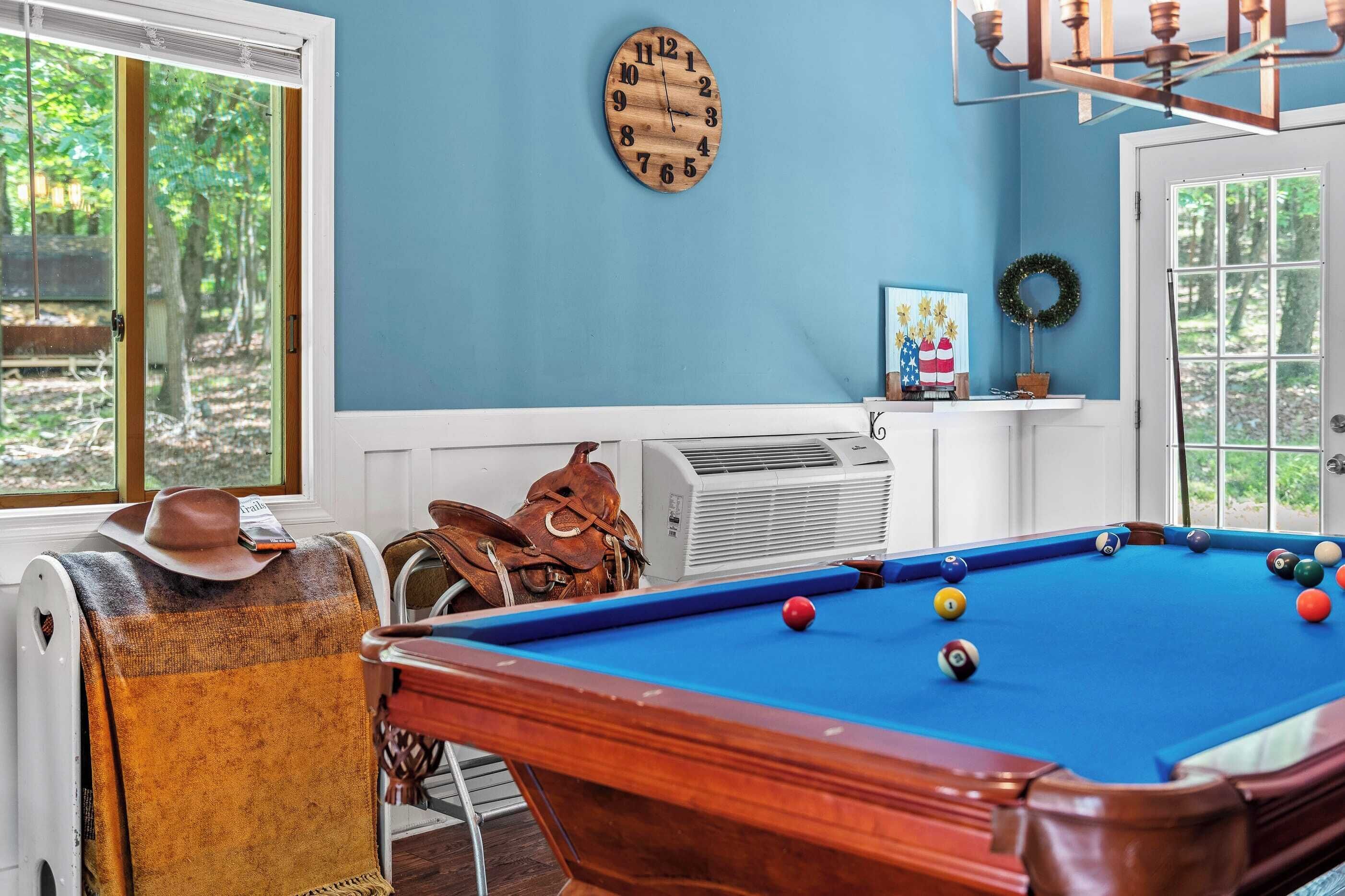 A pool table with balls, a clock, and a fireplace.
