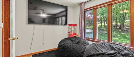 Een kamer met een groot raam, een plafondventilator, een flatscreen-tv en een kruipzak.