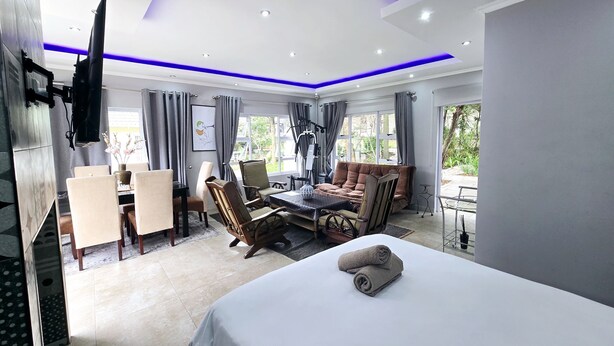 Una habitación de hotel moderna con cama, zona de estar y mesa de comedor.