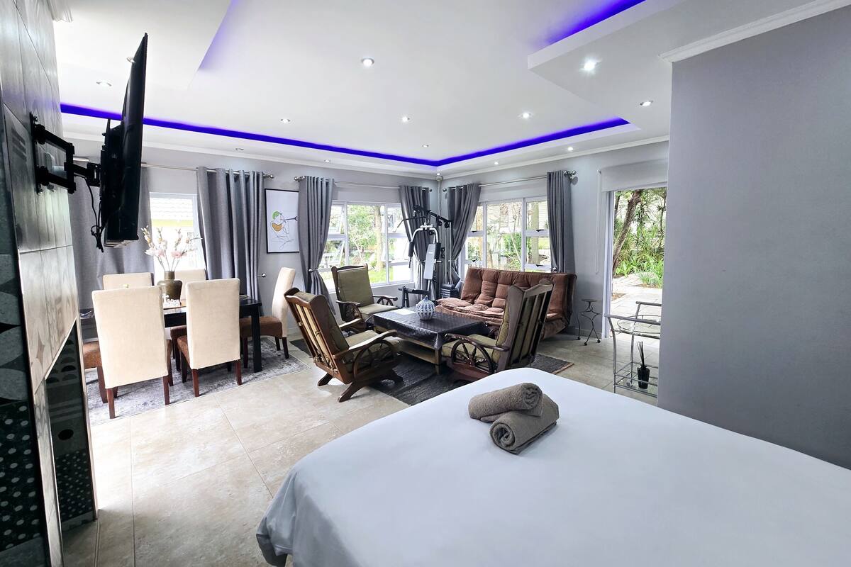 Una habitación de hotel moderna con cama, zona de estar y mesa de comedor.