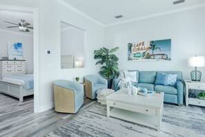 A living room with a white sofa, a blue armchair, a white coffee table, and a ceiling fan.