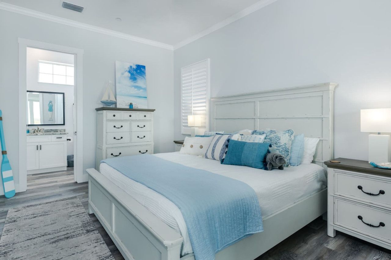 A bedroom with a bed, nightstands, a dresser, and a mirror.
