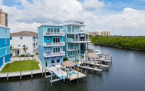 Une propriété riveraine à plusieurs étages, dotée de balcons, d’un quai et d’une pelouse.