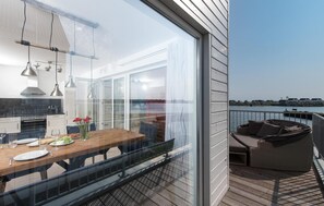 Una cocina moderna con comedor y balcón con vista a un cuerpo de agua.